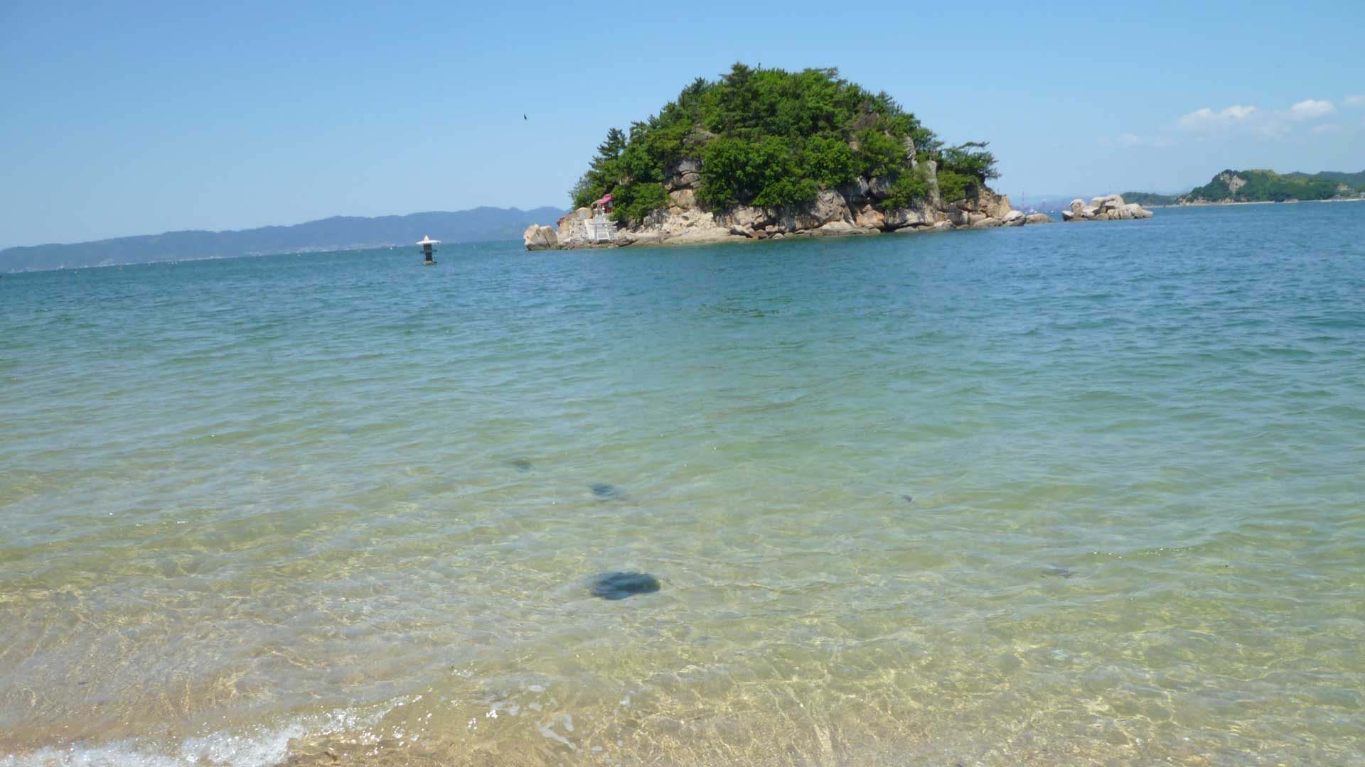 透き通った海と緑の小島が広がる穏やかな海辺の風景