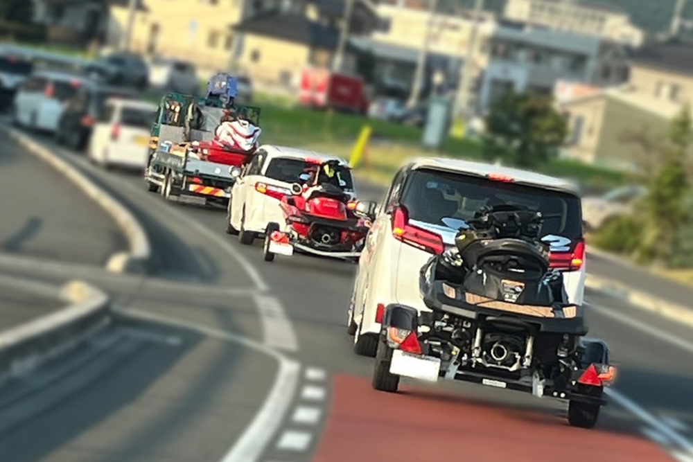 水上バイクを牽引する車が道路を走行している写真